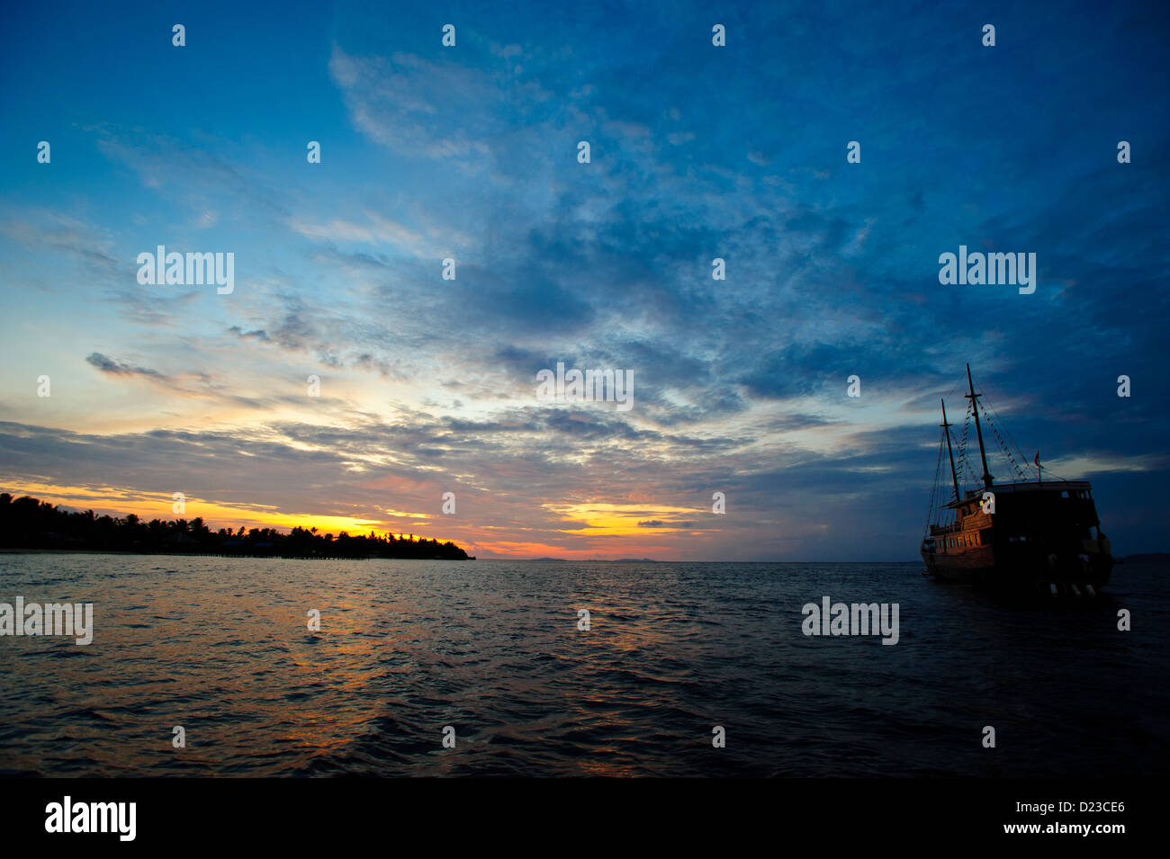 Lo yacht di fronte ad un bellissimo tramonto in Raja Ampat da un isola. Calma giorno in Raja Ampat Papua Nuova Guinea Indonesia Foto Stock