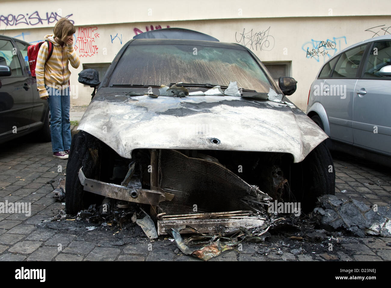 Berlino, Germania, ragazza guarda un'auto bruciata in Berlin-Mitte Foto Stock