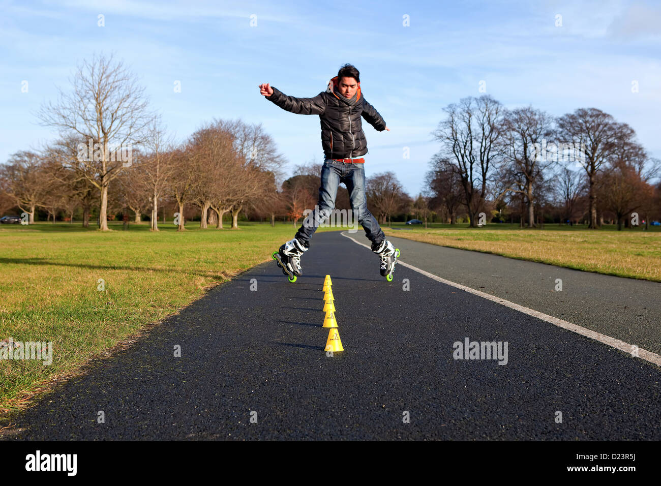 Un ragazzo asiatico eseguito un trucco durante il freestyle slalom formazione nel Phoenix Park di Dublino, Irlanda. Foto Stock