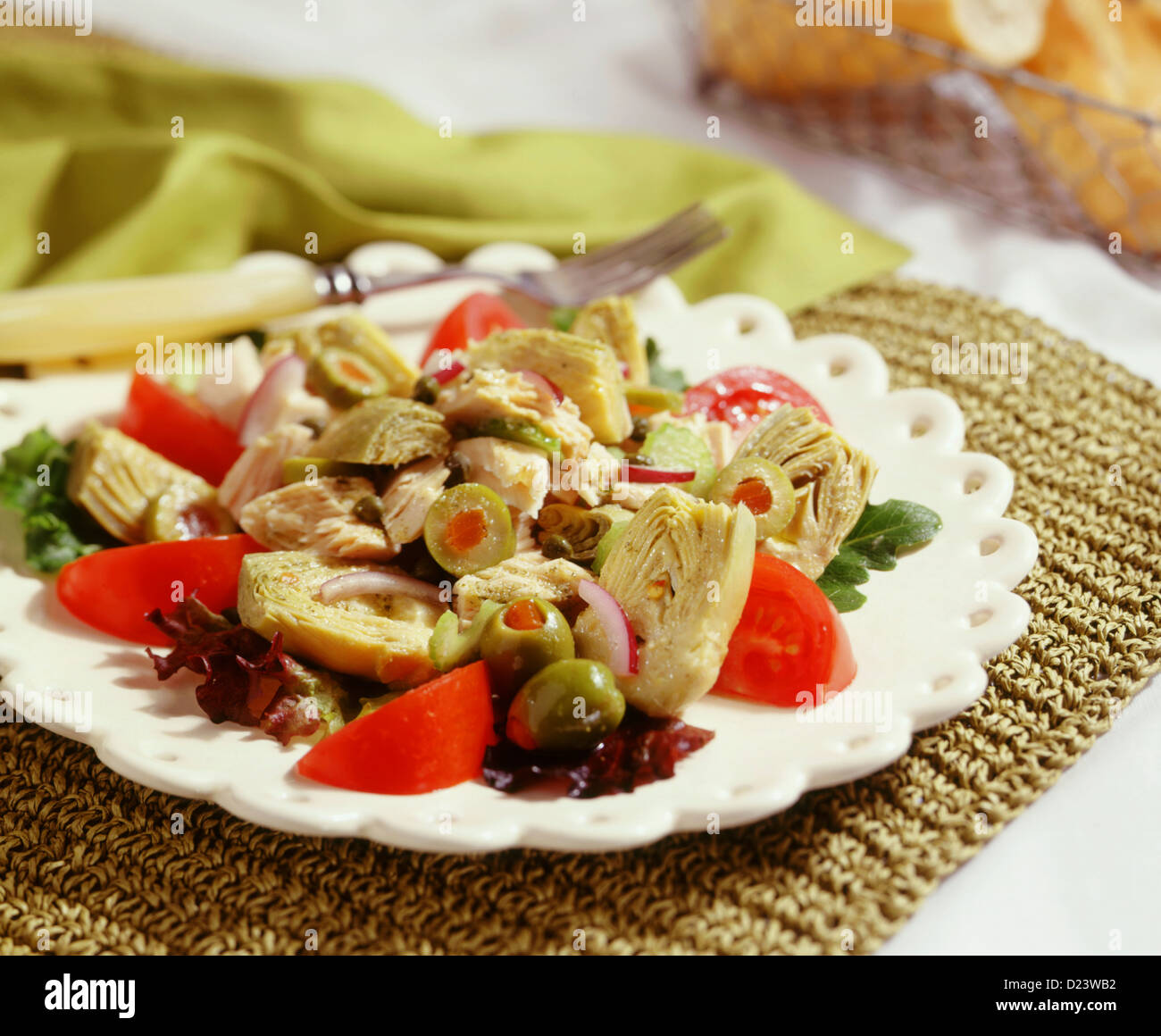 Un carciofo con insalata di pomodori cipolle e olive verdi Foto Stock