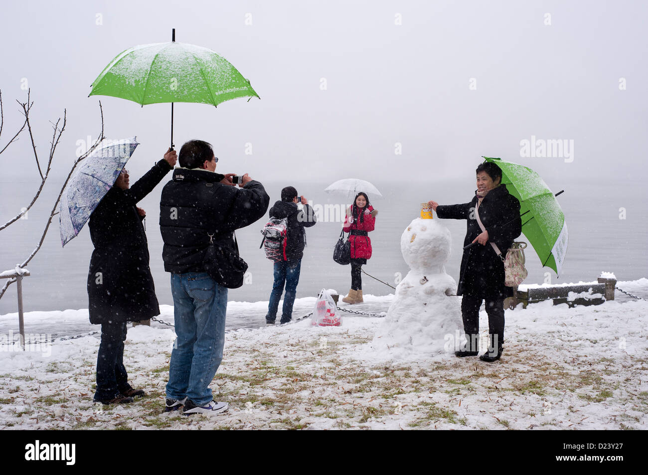 I turisti cinesi in posa accanto a un pupazzo di neve a West Lake, Hangzhou, Cina Foto Stock