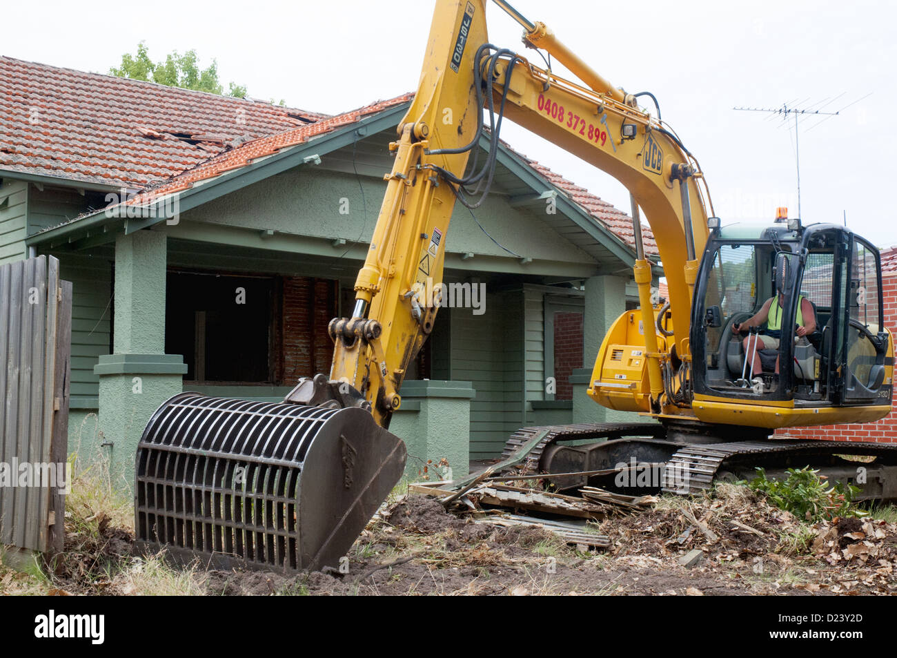 Demolizione contraente inizia a lavorare su un 1920s 'californiano " Bungalow casa di legno nella periferia di Melbourne, Australia Foto Stock