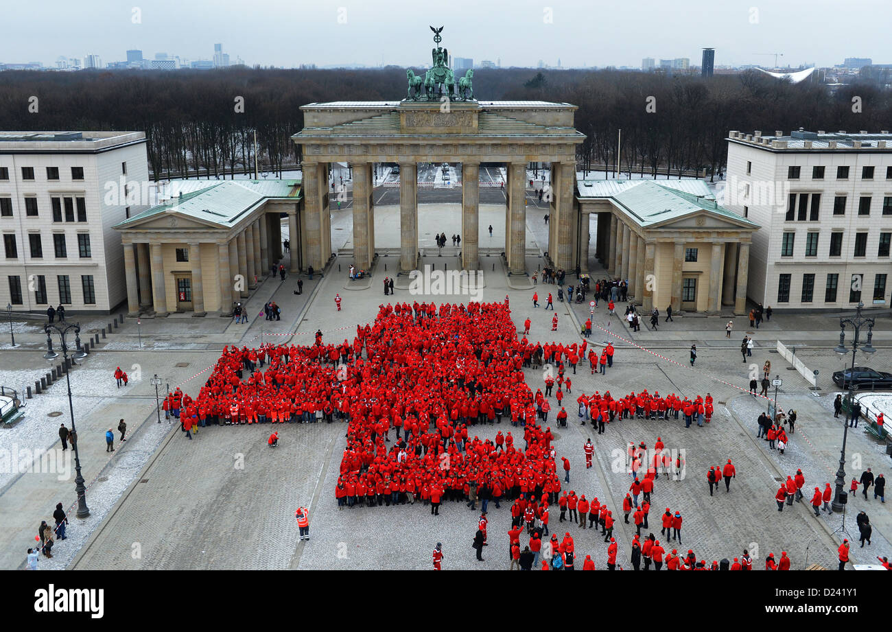 1.800 membri della Croce Rossa tedesca (DRK) vestita in rosso formano una grande croce alla Porta di Brandeburgo a Berlino, Germania, 13 gennaio 2013. La performance è parte di questo anno il centocinquantesimo anniversario. Foto: Britta Pedersen Foto Stock