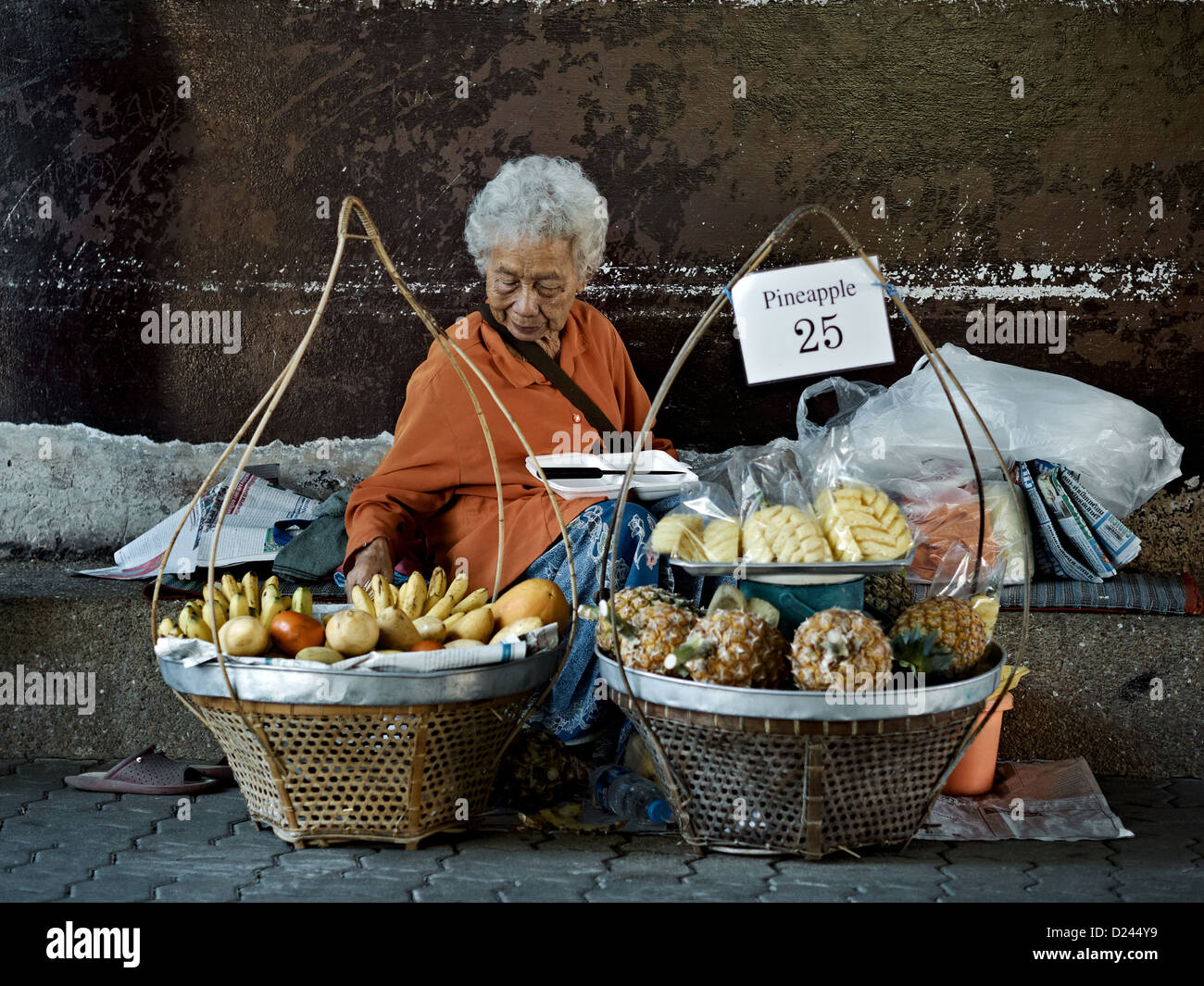 Donna anziana strada fornitore di prodotti alimentari per la vendita di frutta. Thailandia SUDEST ASIATICO Foto Stock