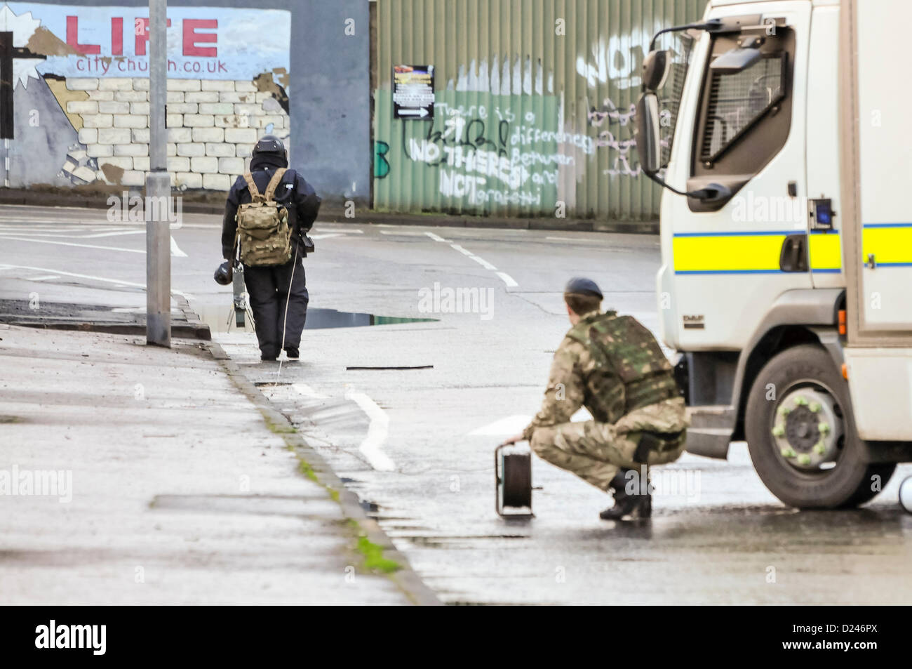 Belfast, Irlanda del Nord, Regno Unito. 14 gennaio 2013. Esercito da ATO 321 Squadrone, 11 EOD reggimento, vestito in un a prova di bomba suit cammina verso un dispositivo sospetto che trasportano un esplosione controllata "suino stick'. Il suo collega contiene una bobina del cavo per il cavo di detonazione. Foto Stock