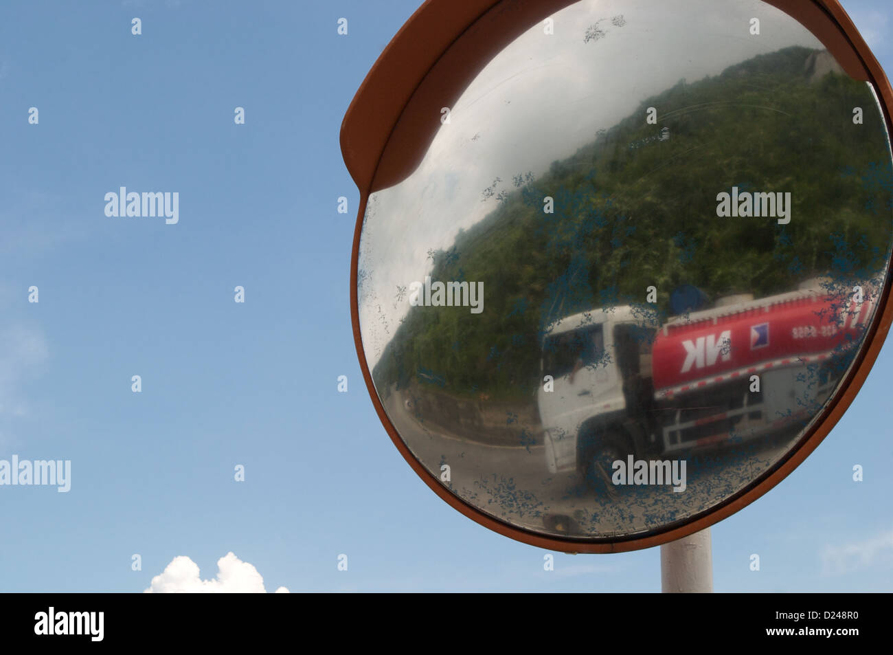 Una petroliera visto attraverso il riflesso di uno specchio stradale si fa strada l'Hai Van Pass, Vietnam Foto Stock