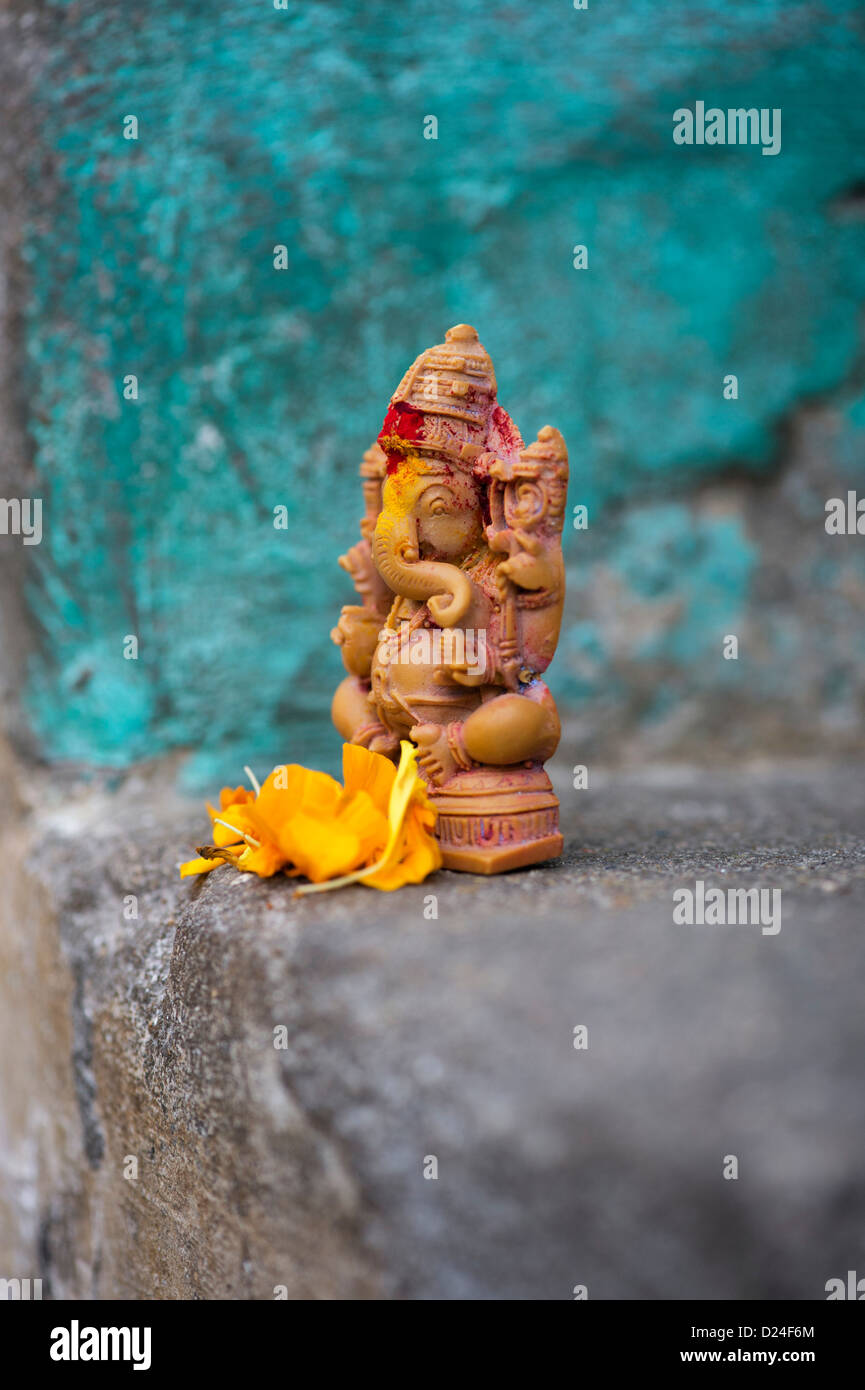 Elefante indù Dio. Signore Ganesha statua e petali di fiori contro la parete colorata. India Foto Stock
