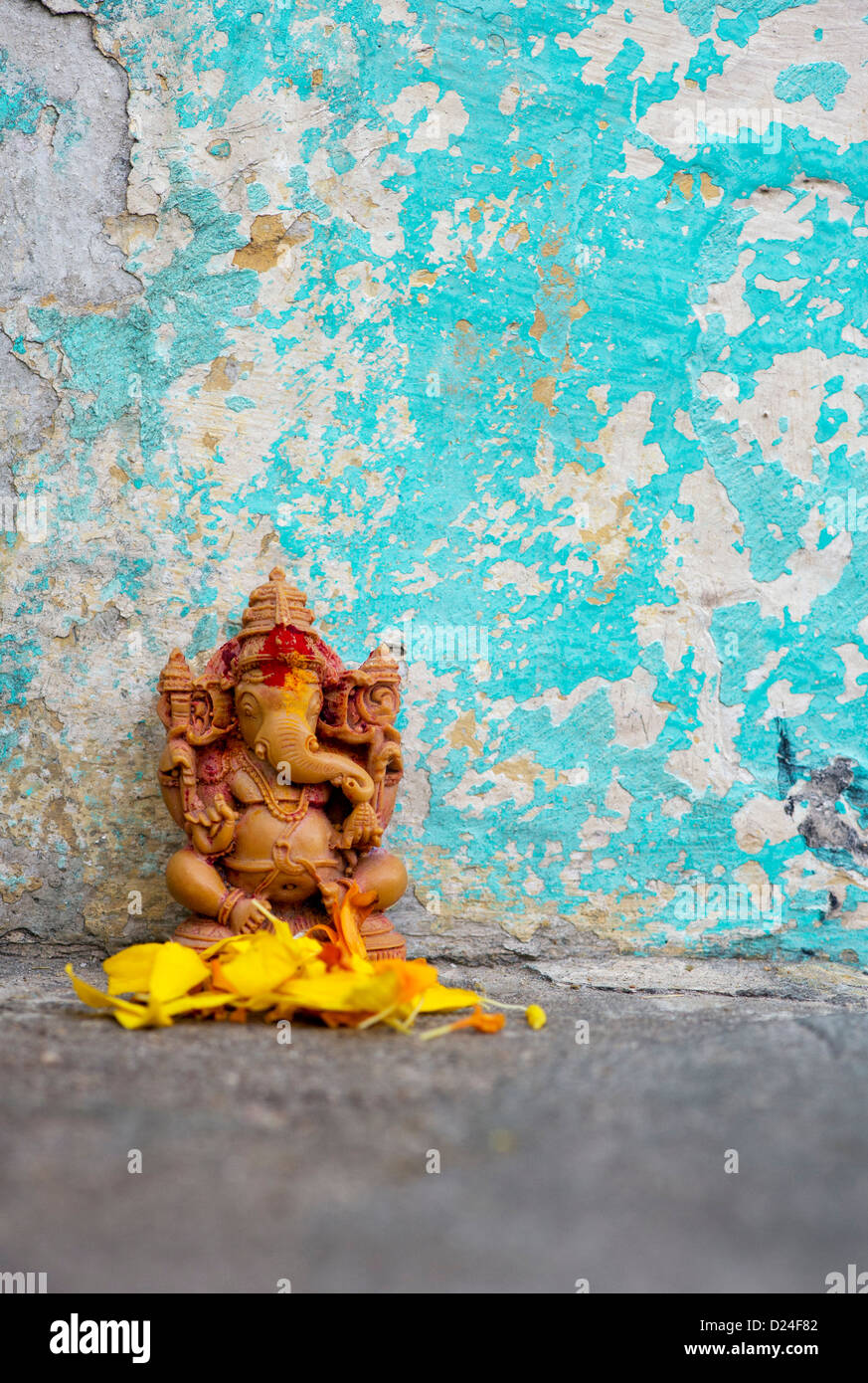 Elefante indù Dio. Signore Ganesha statua e petali di fiori contro la parete colorata. India Foto Stock