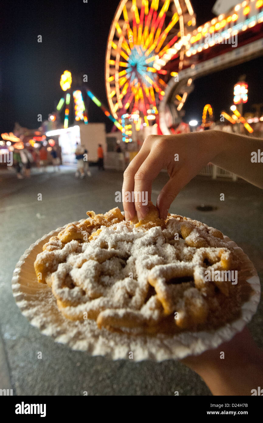 Persona di mangiare la torta di imbuto, godendo il parco di divertimenti al Maryland State Fair, Timonium MD Foto Stock