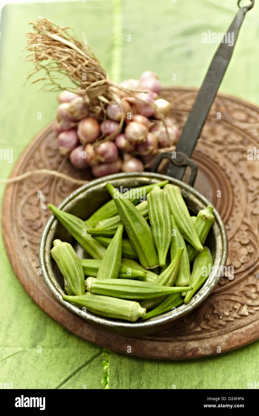 Un piatto di okra e un mazzetto di scalogni Foto Stock