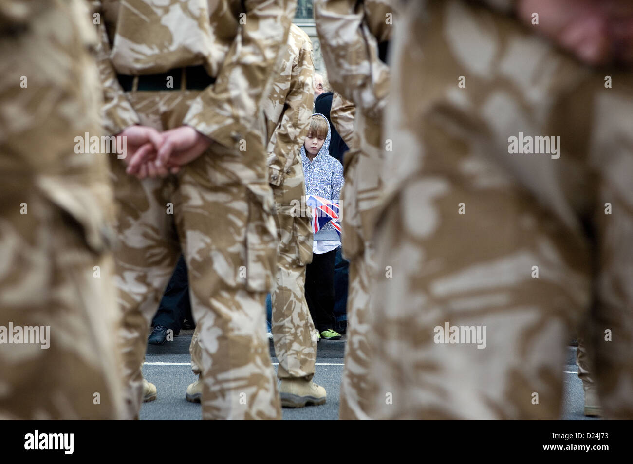 Un bambino piccolo visto dietro le gambe dei soldati britannici. Foto Stock