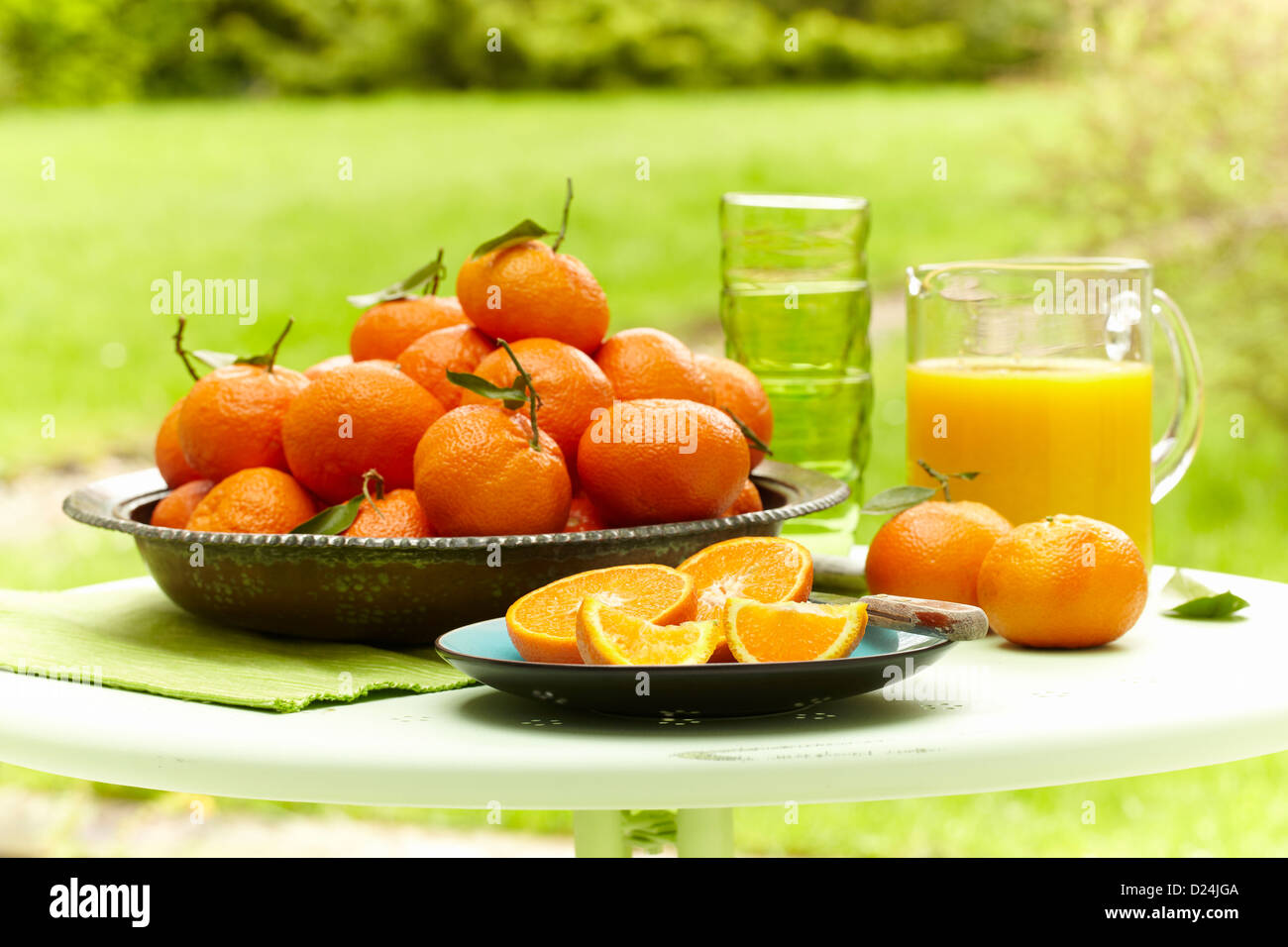 Una ciotola di arance e la brocca di succo d'arancia fresco all'aperto Foto Stock