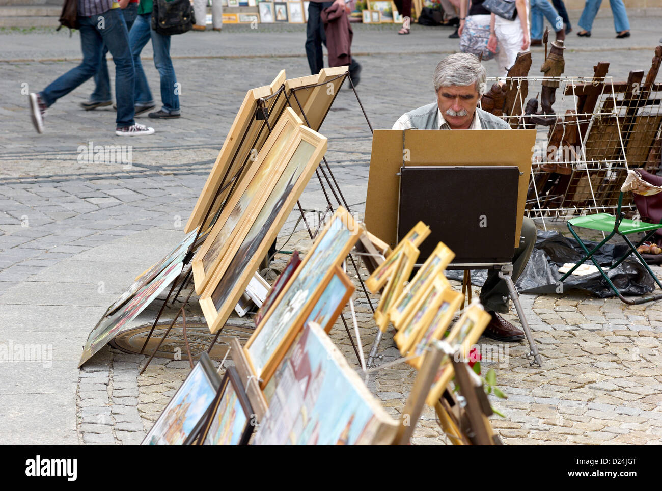 Wroclaw, Polonia, un pittore di strada in mezzo ai suoi dipinti nel marketplace Foto Stock