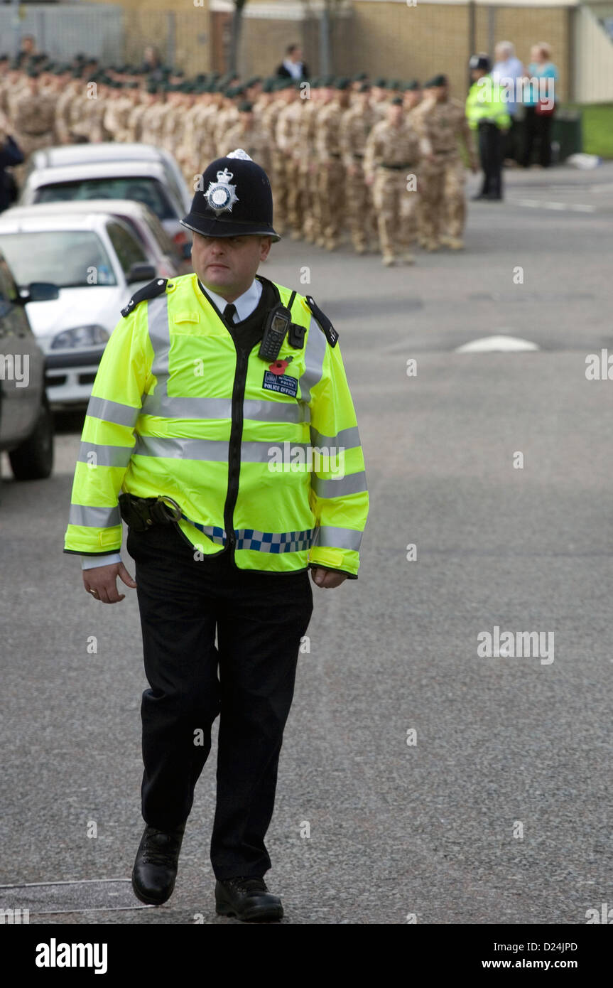 Un poliziotto a piedi nella parte anteriore di una colonna di marciare soldati britannici. Foto Stock