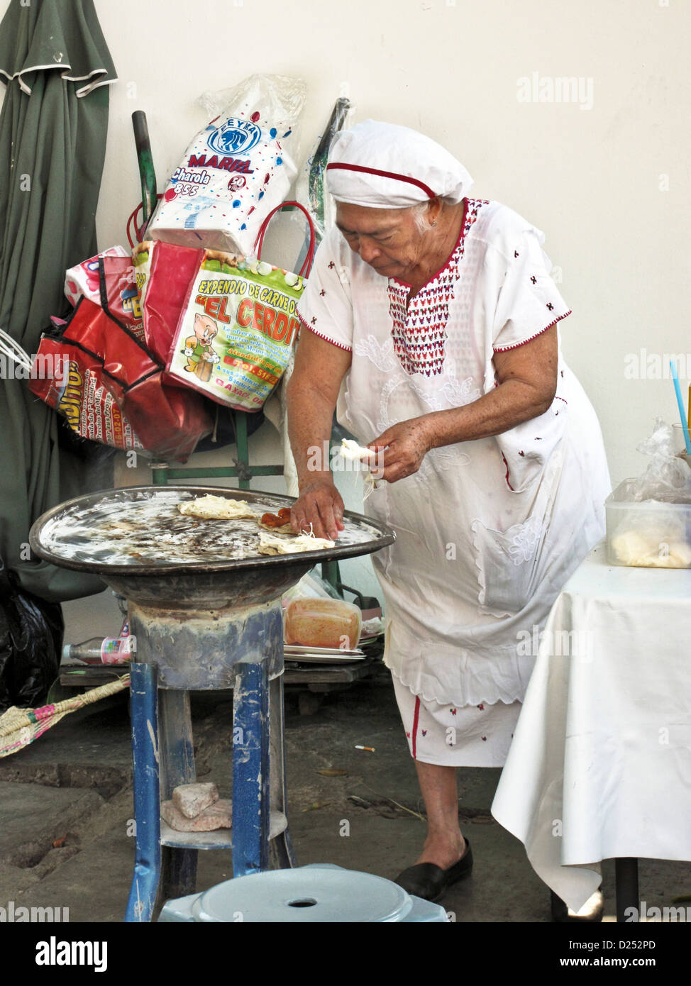 Immacolata vecchia donna venditore aggiunge la stringa Oaxacan formaggi tacos cucinando fuori sul marciapiede stufa Oaxaca de Juarez Mexico Foto Stock