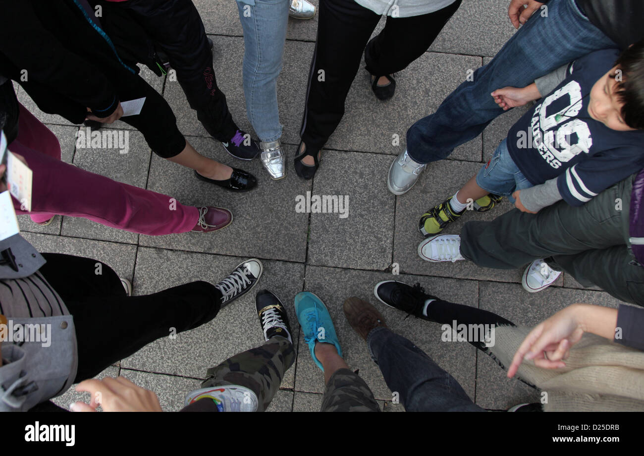 Si tratta di una foto vista dalla cima di molte persone a mettere i loro piedi a fianco a fianco in cerchio per mostrare le loro scarpe. Si tratta di creative. Foto Stock