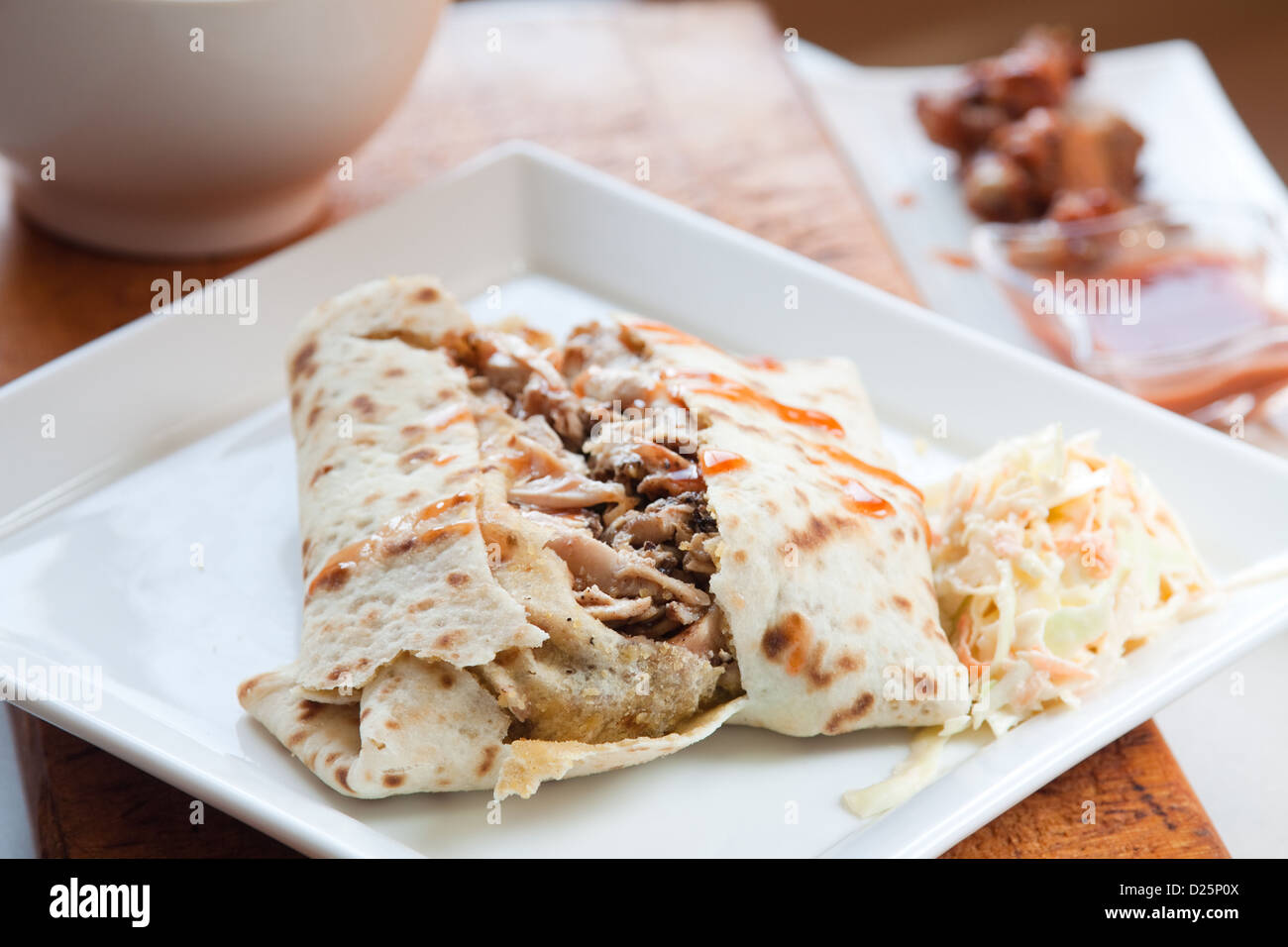Lo stile caraibico pollo jerk servita nei tradizionali roti e spruzzata con dolci salsa calda. Servito con un lato della coleslaw. Foto Stock