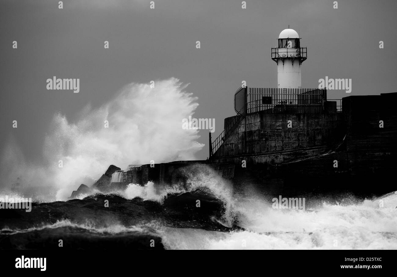 Heavy onde infrangersi contro la parete del mare e del faro a sud di gare su Teesside in Inghilterra durante il mare grosso. Foto Stock