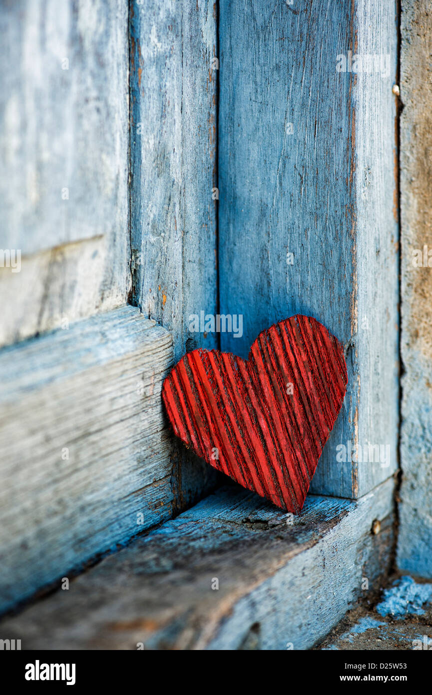 Red buccia di cocco corteccia forma di cuore su un vecchio vestito di stracci dipinte di blu porta. India Foto Stock