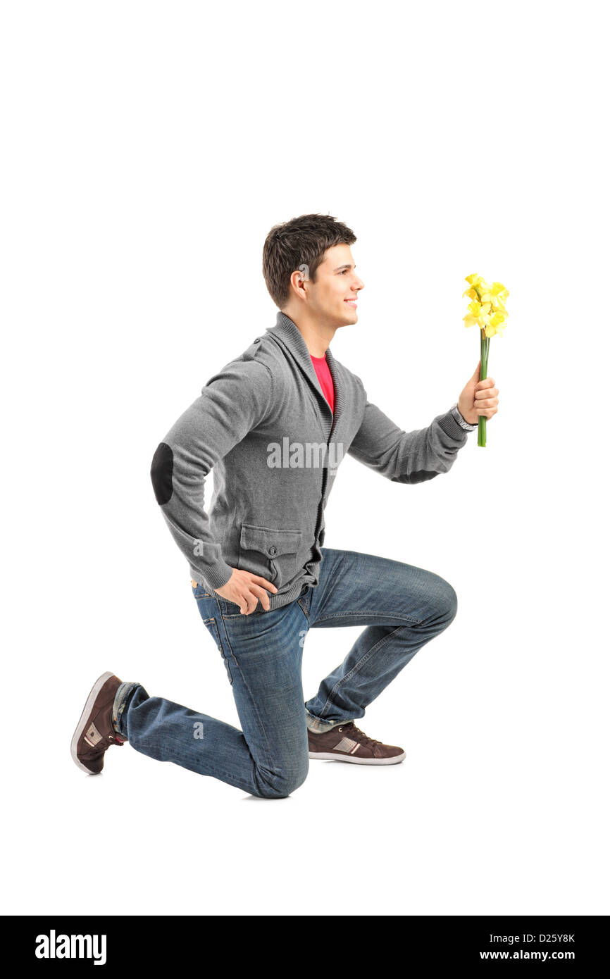 Un maschio in ginocchio e tenendo un fiore isolato su sfondo bianco Foto Stock