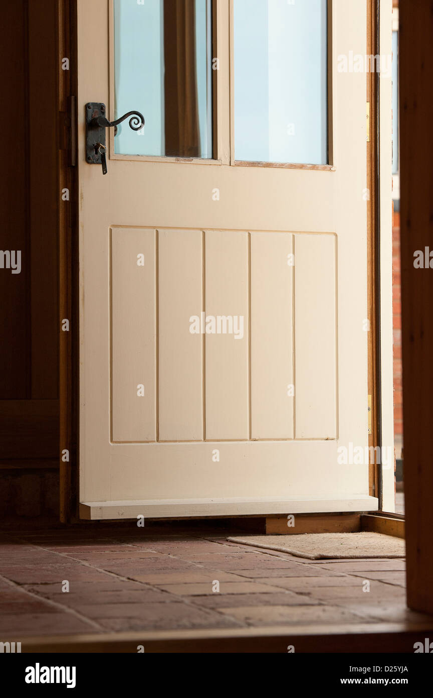 Apertura della porta in un piastrellate hall di entrata in una nuova Barn convertito in Inghilterra rurale. Foto Stock