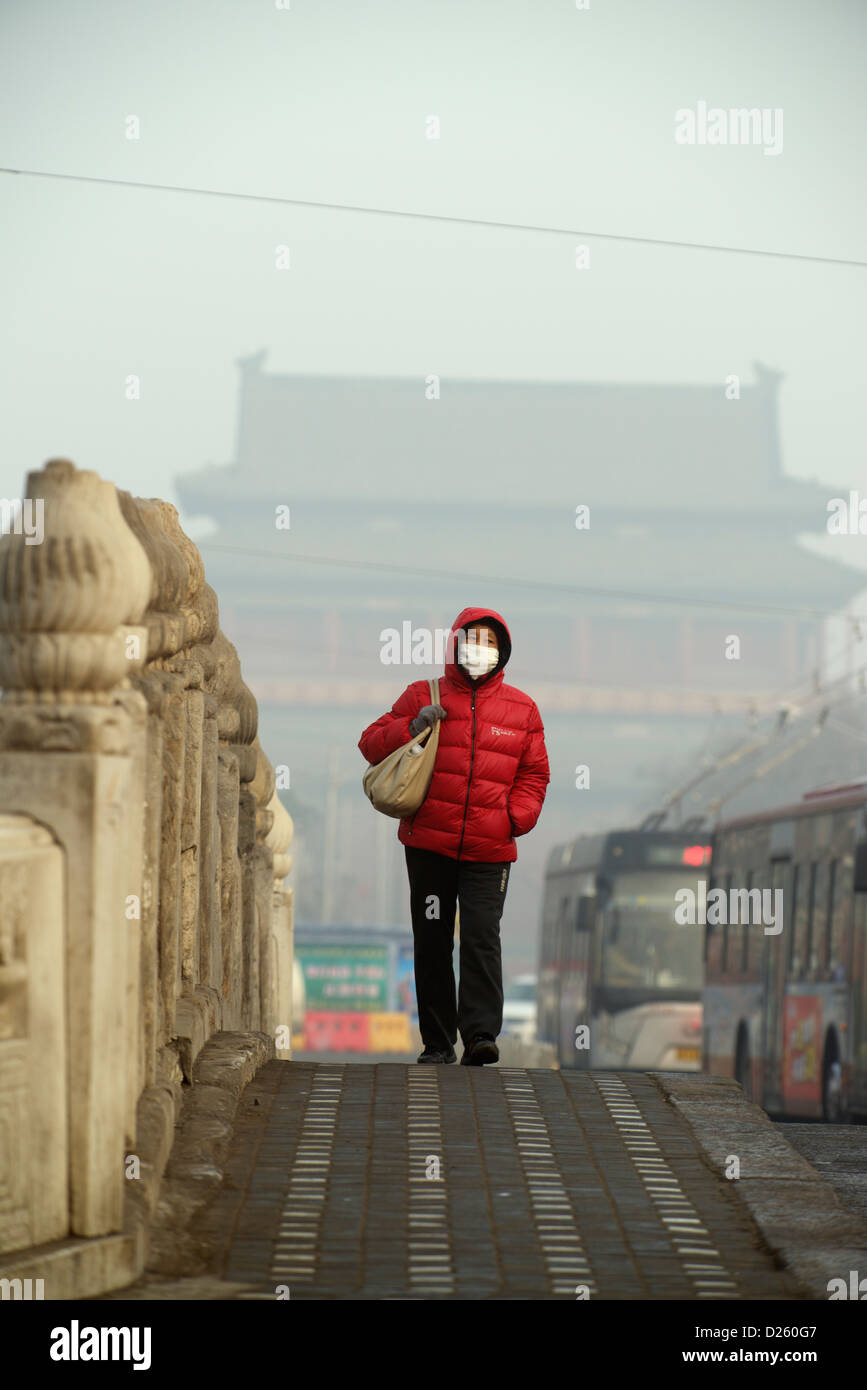 Una donna cinese indossa una maschera su un ponte a Pechino in Cina, 14 gennaio 2013. Foto Stock