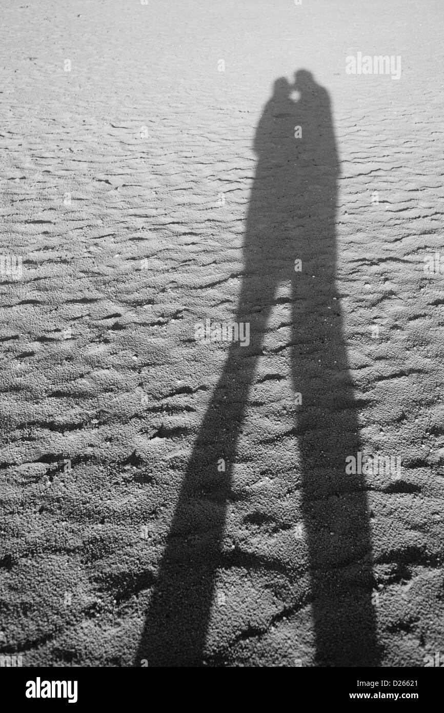 Due persone baciare le ombre cadono oltre la spiaggia Foto Stock
