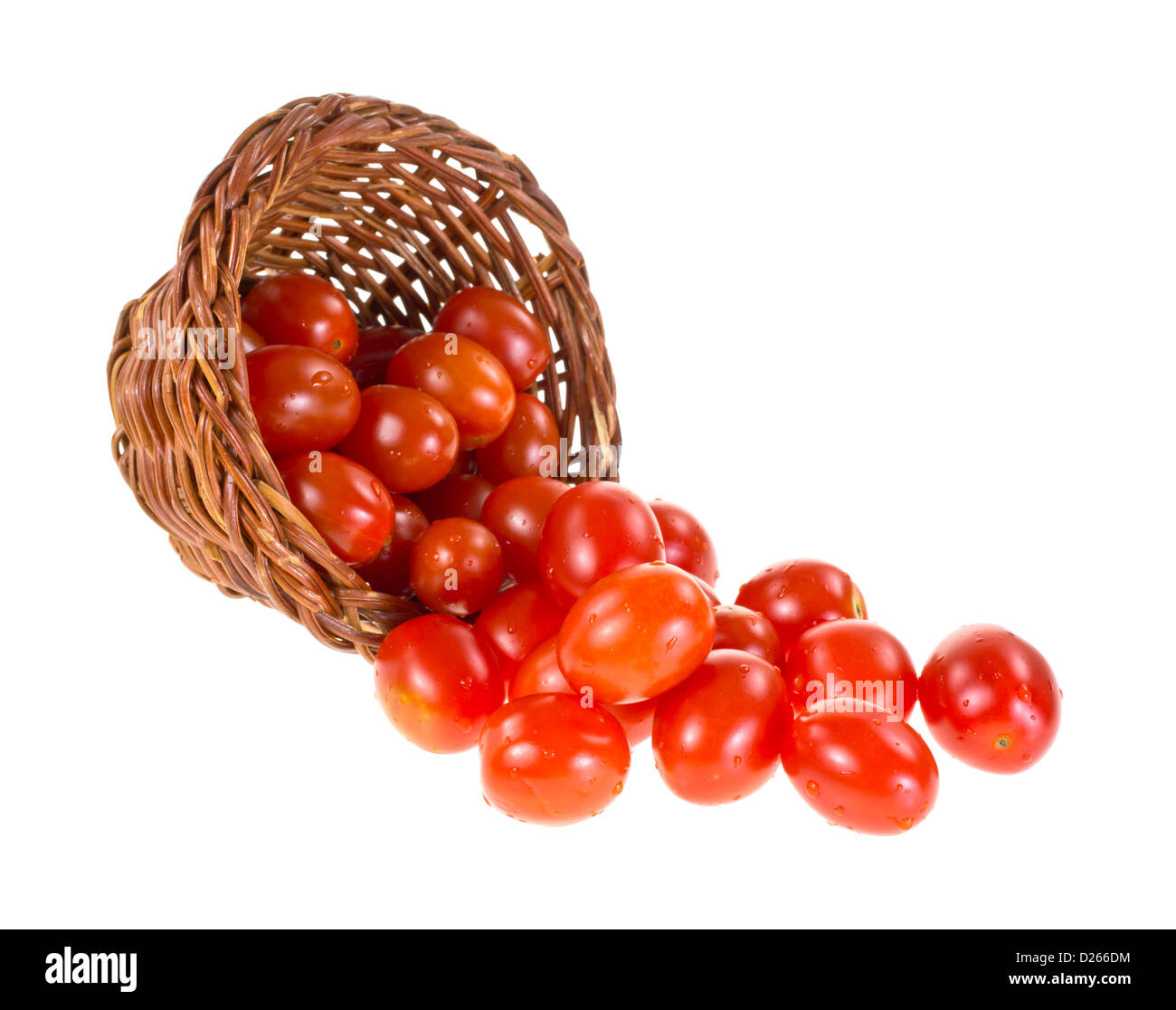 Diversi piccoli pomodori uva fuoriuscita da un cesto di vimini su uno sfondo bianco. Foto Stock