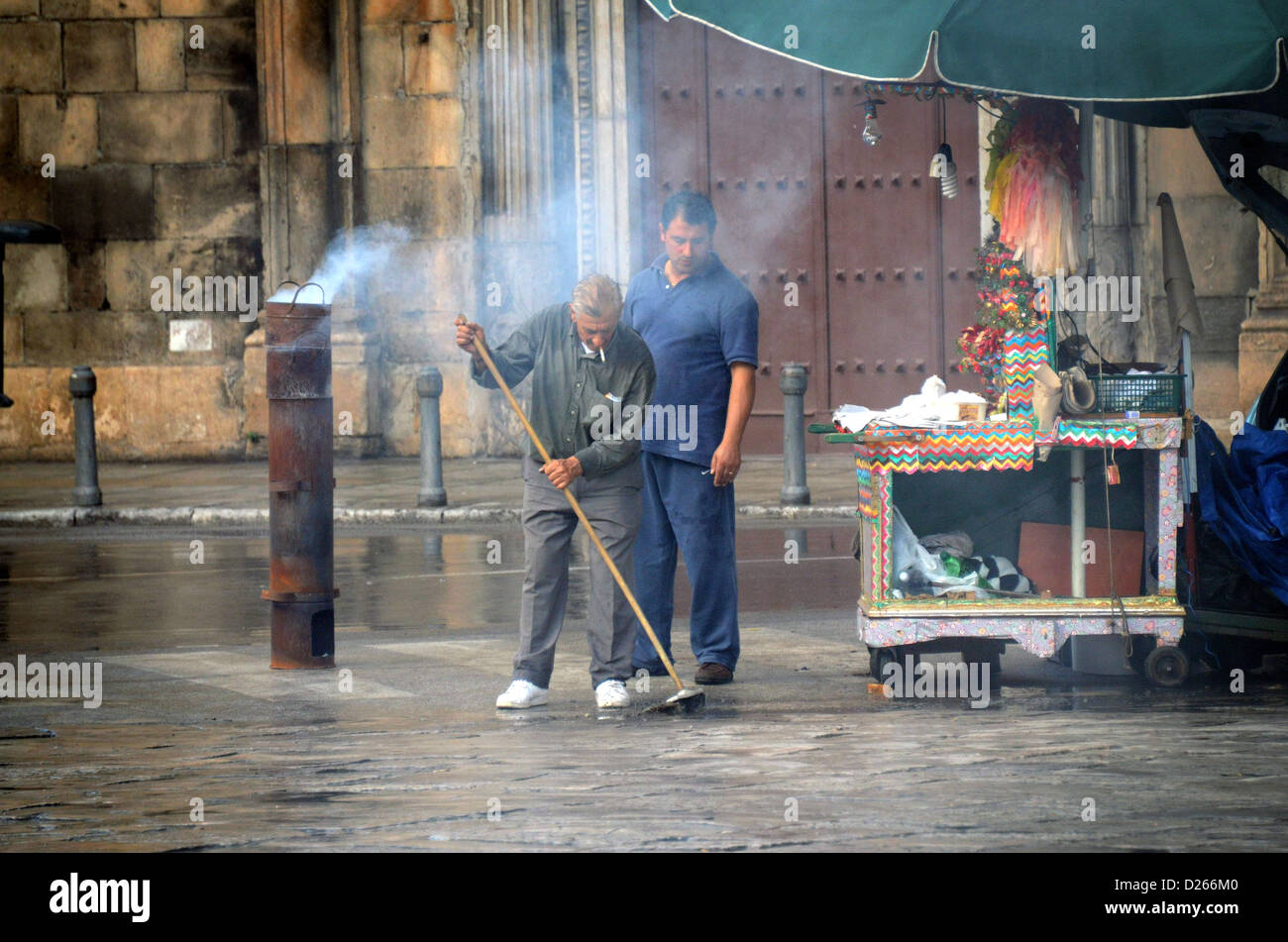 Venditori ambulanti che scopa intorno stallo di castagno in strada a Palermo Foto Stock
