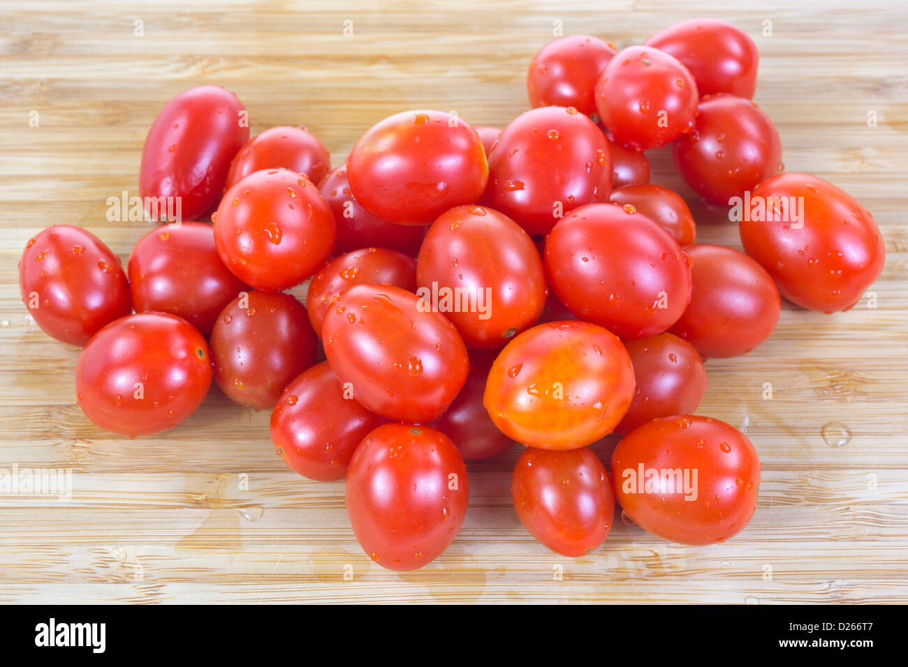 Un gruppo di uva pomodori appena risciacquato su un legno tagliere. Foto Stock