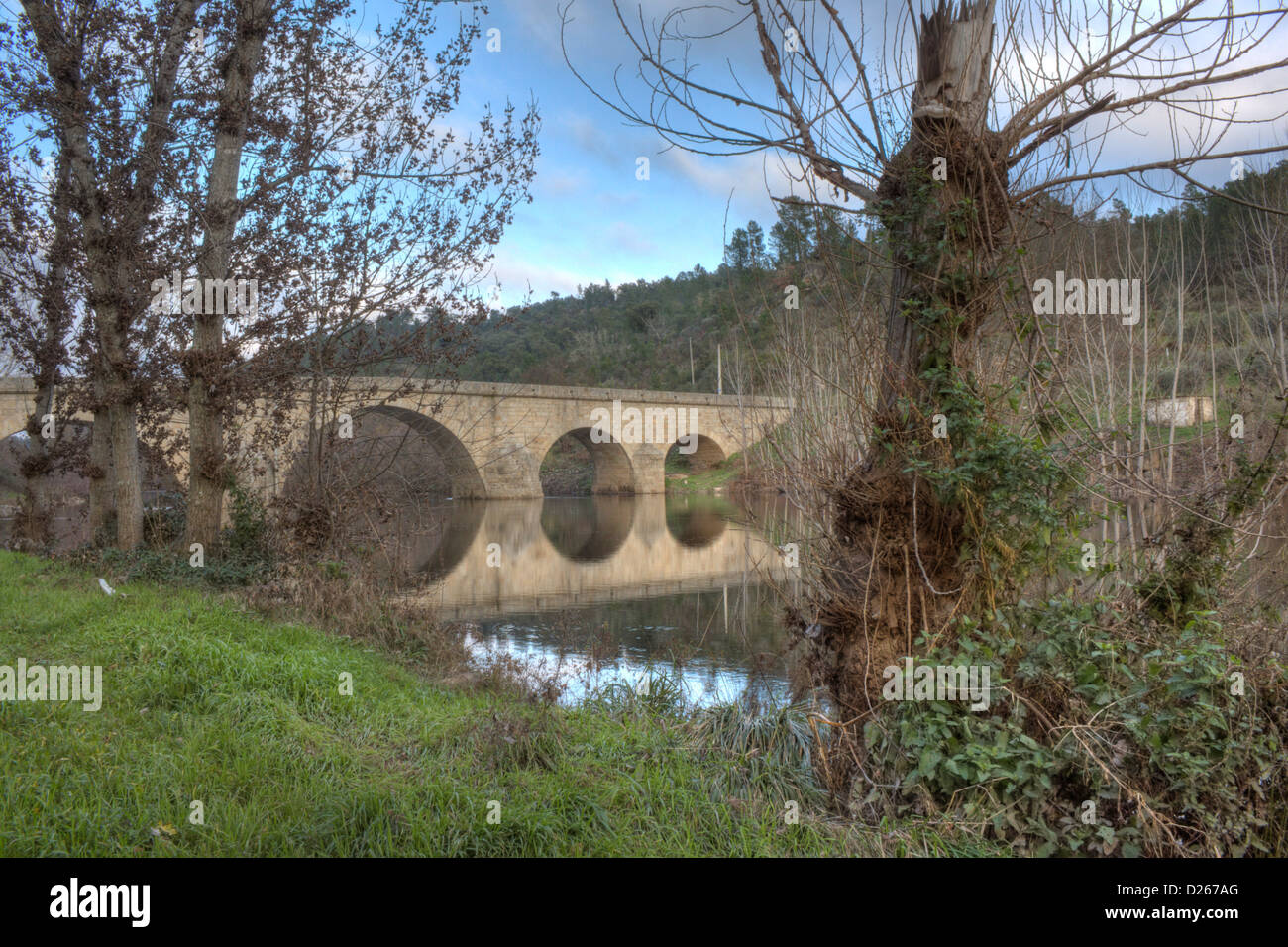 Un antico ponte in pietra con il cielo si riflette nel fiume di acqua Foto Stock