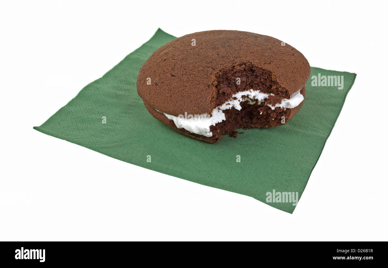 Un cioccolato whoopie pie con la glassa che è stato picchiato su uno sfondo bianco. Foto Stock