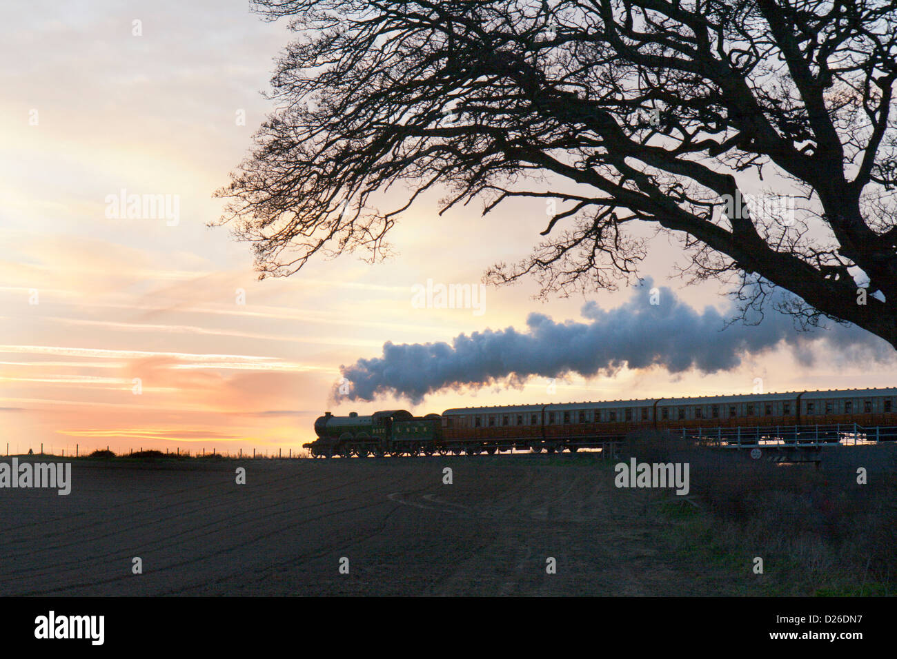 Locomotiva a vapore la trazione di un treno passeggeri sulla North Norfolk Railway - tramonto Foto Stock
