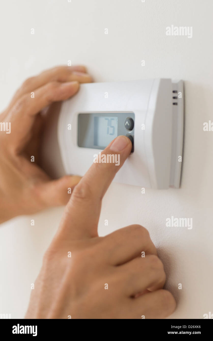 Stati Uniti d'America, New Jersey, Jersey City, mano modificando le impostazioni sul termostato dell'aria condizionata Foto Stock