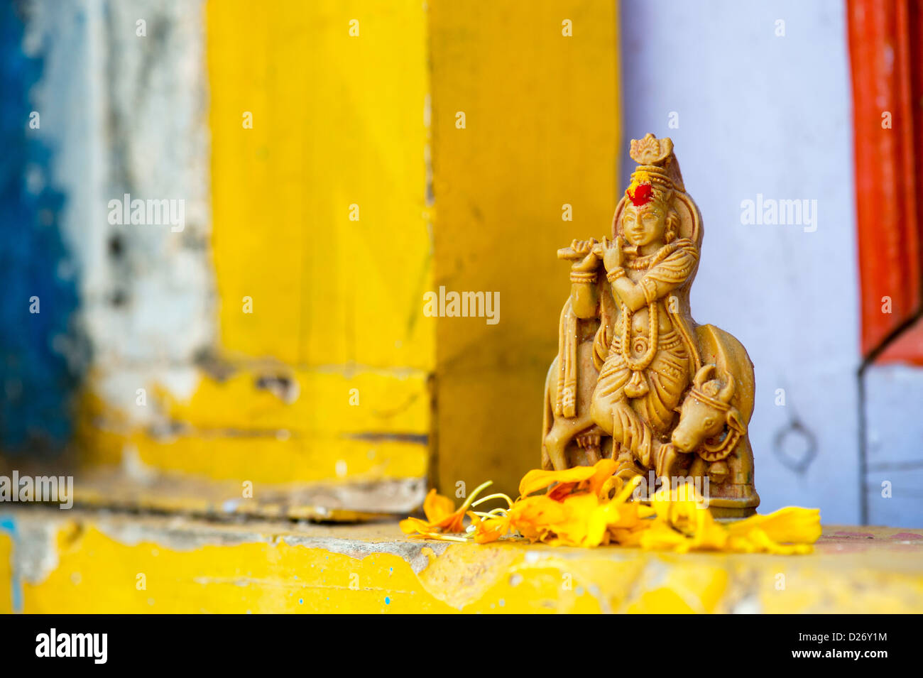 Krishna statua e petali di fiori al di fuori del tempio del villaggio porta. India Foto Stock