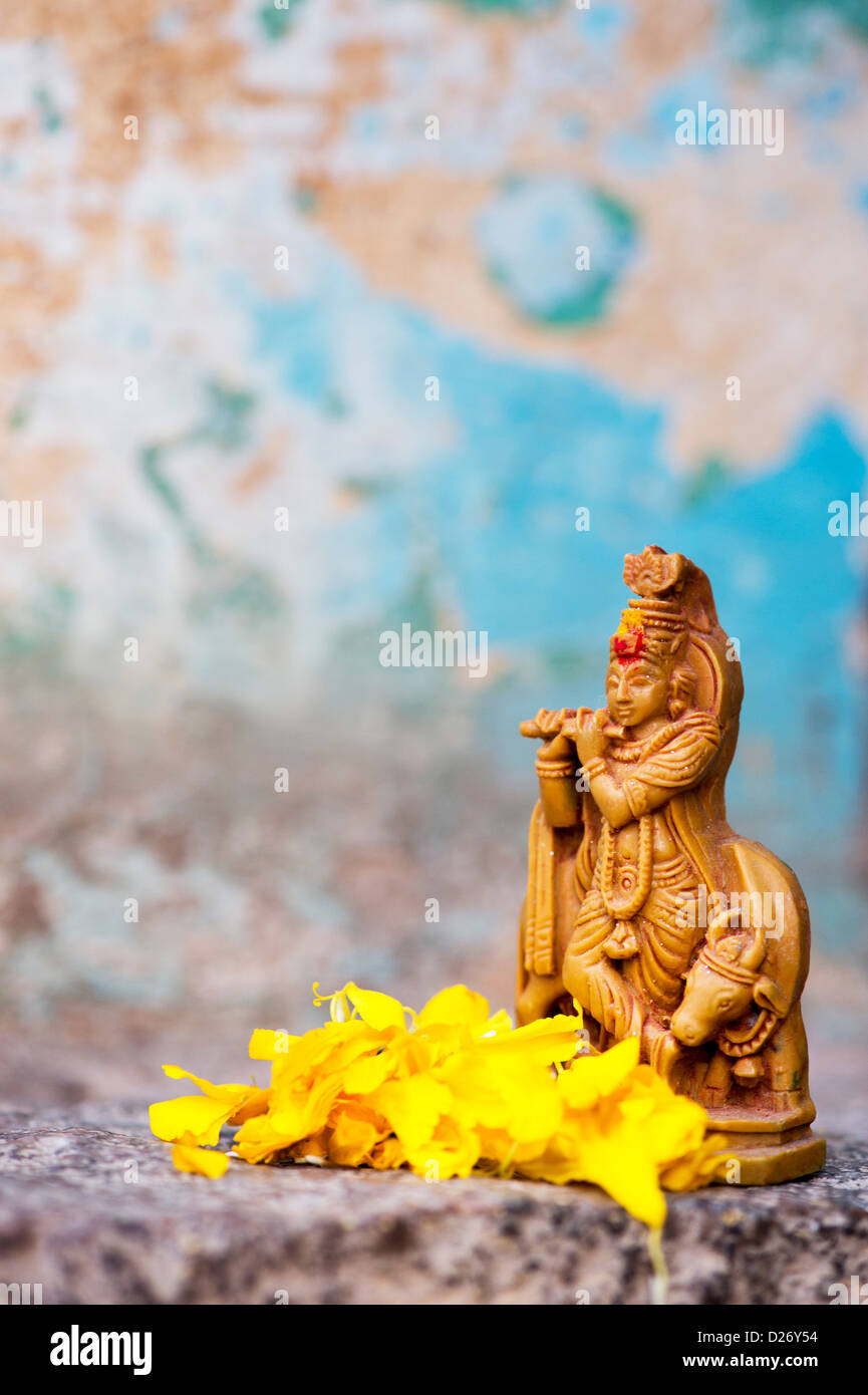 Krishna statua e petali di fiori contro la parete colorata. India Foto Stock