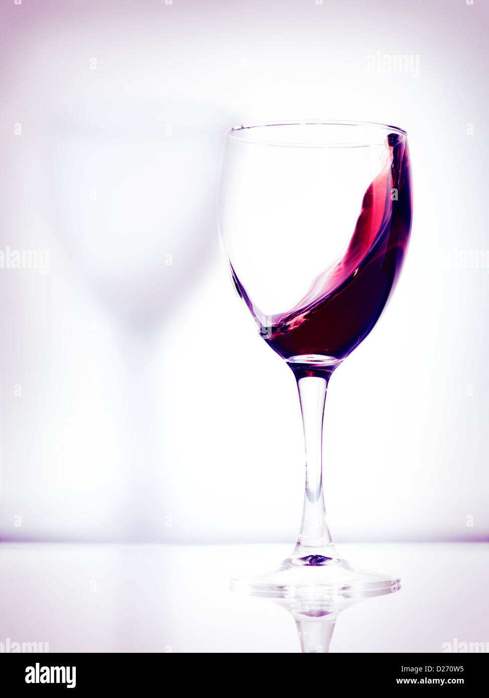 Vino rosso in un vetro foto artistiche isolato su bianco luminoso con sfondo rosa Foto Stock