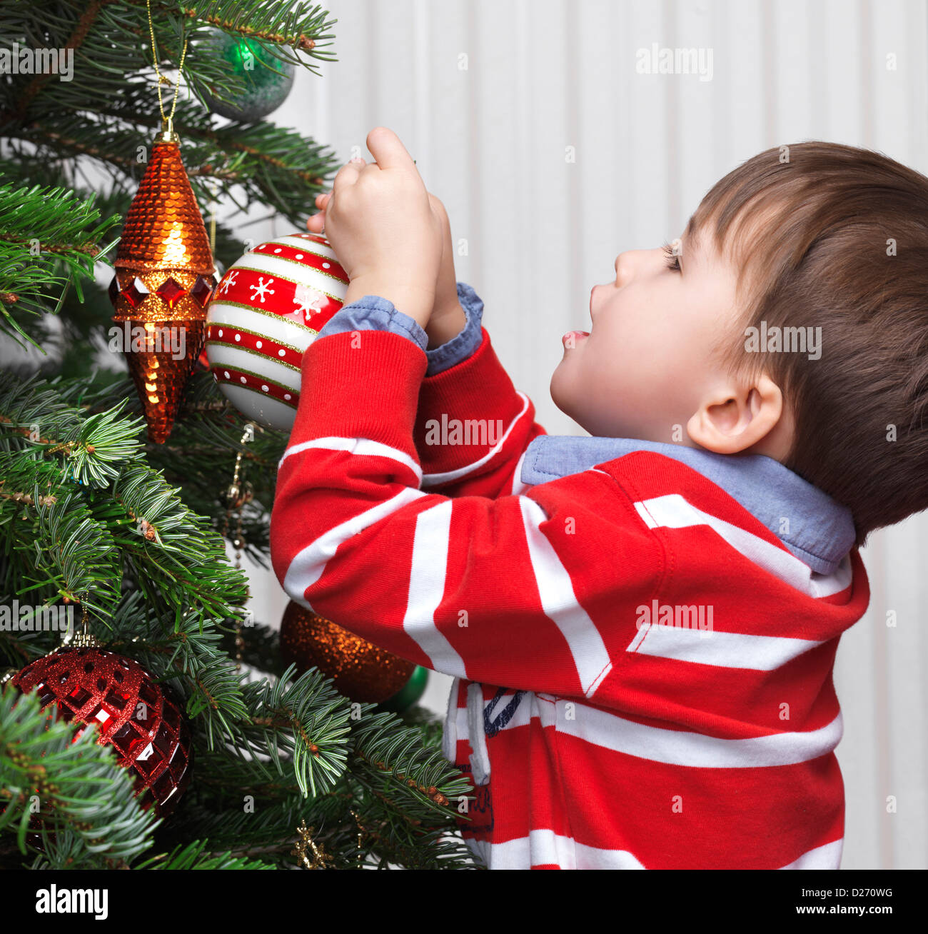 Little Boy decorare un albero di Natale a casa. Tre anni di bambino con ornamento di Natale. Foto Stock