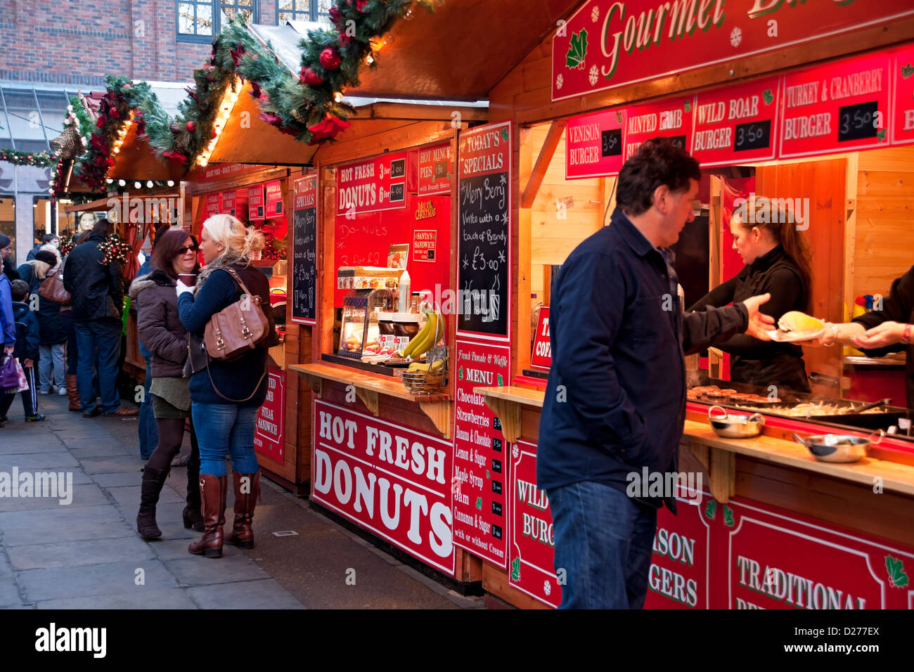 Persone turisti visitatori al mercatino di Natale bancarelle che vendono via takeaway Cibo in inverno York North Yorkshire Inghilterra UK Regno Unito La Gran Bretagna Foto Stock