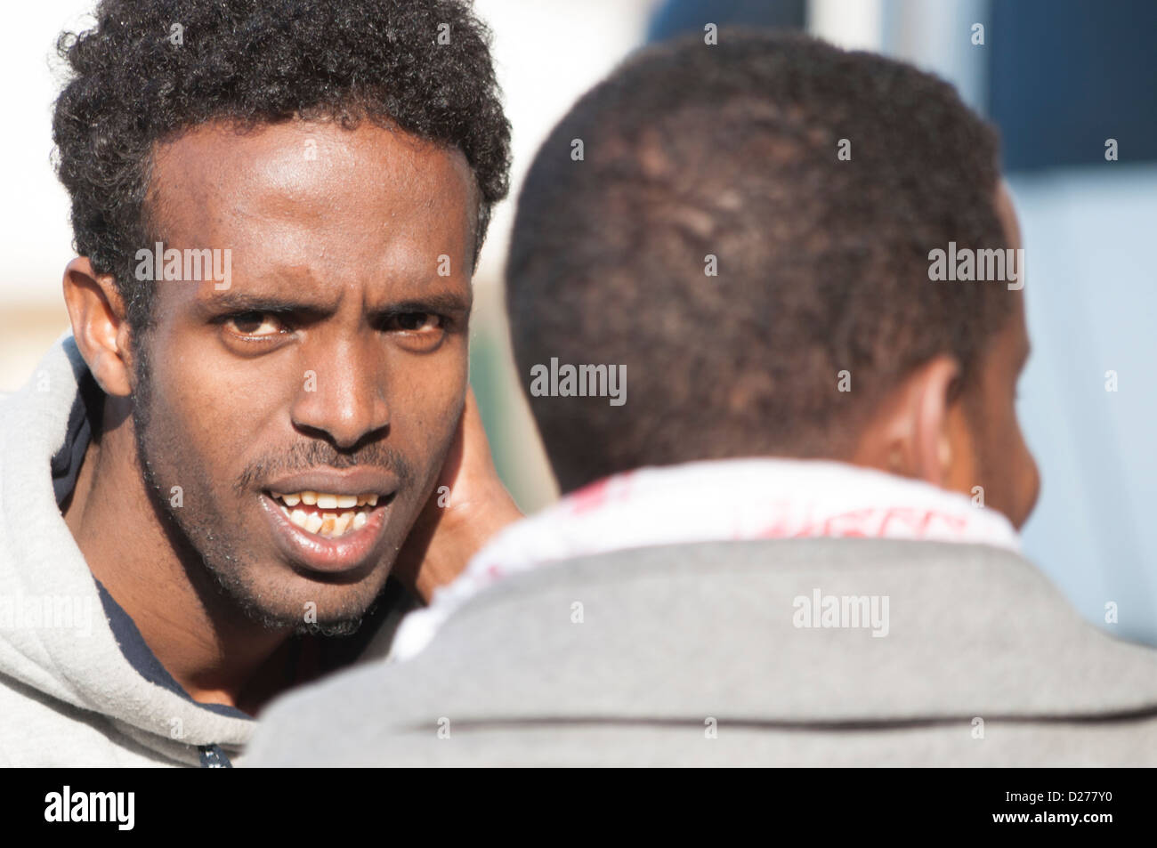 Nero lavoratore africano chiacchierando con gli amici in un cafe' sul marciapiede Foto Stock