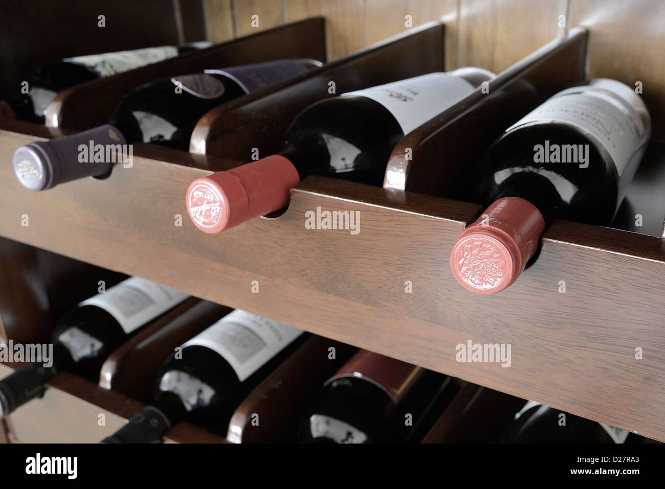 Una raccolta di diverse bottiglie di vino rosso sul rack in legno. Foto Stock