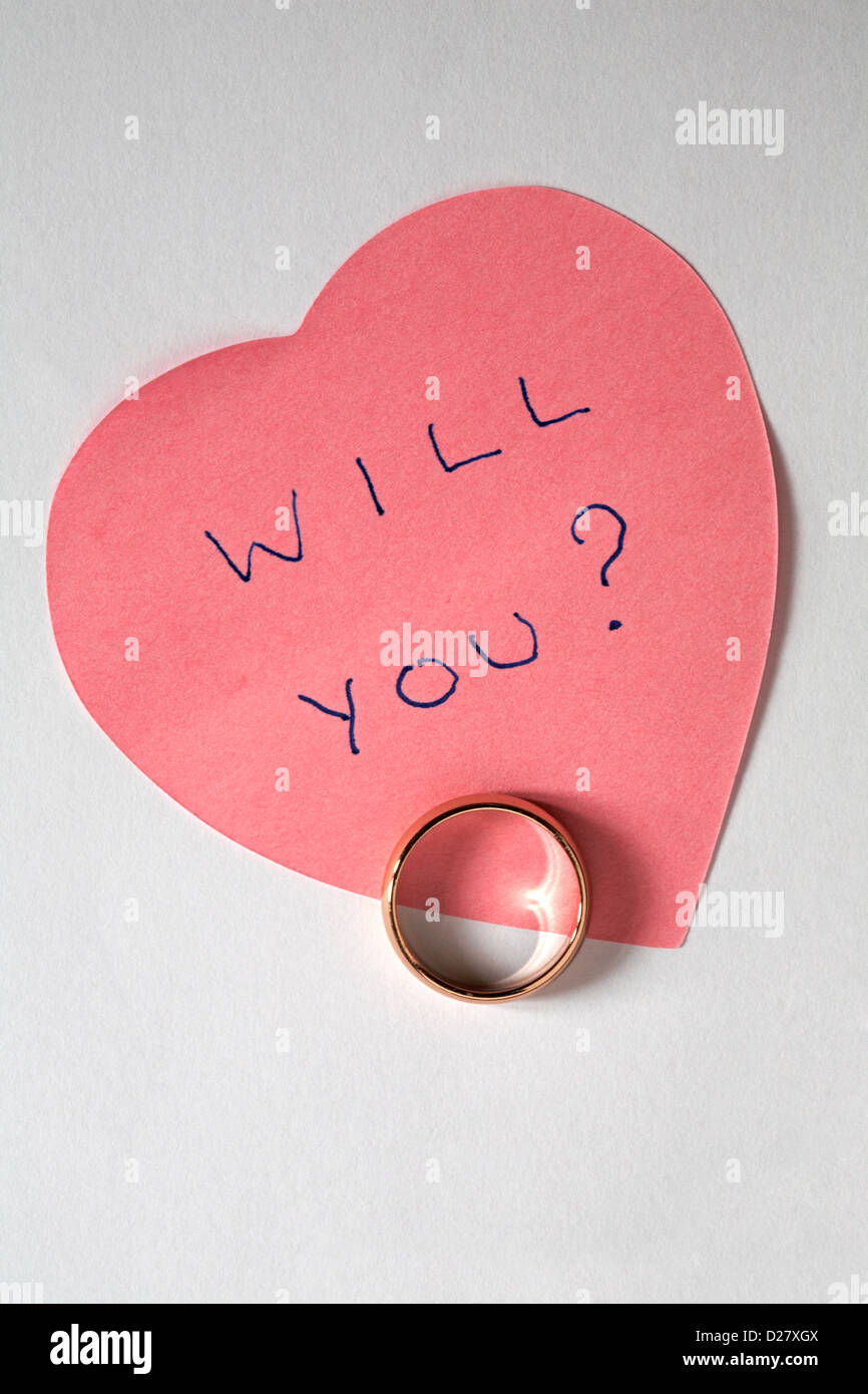 Sarà lei? Scritto su rosa a forma di cuore post-it con anello di nozze - proposta di matrimonio isolati su sfondo bianco Foto Stock