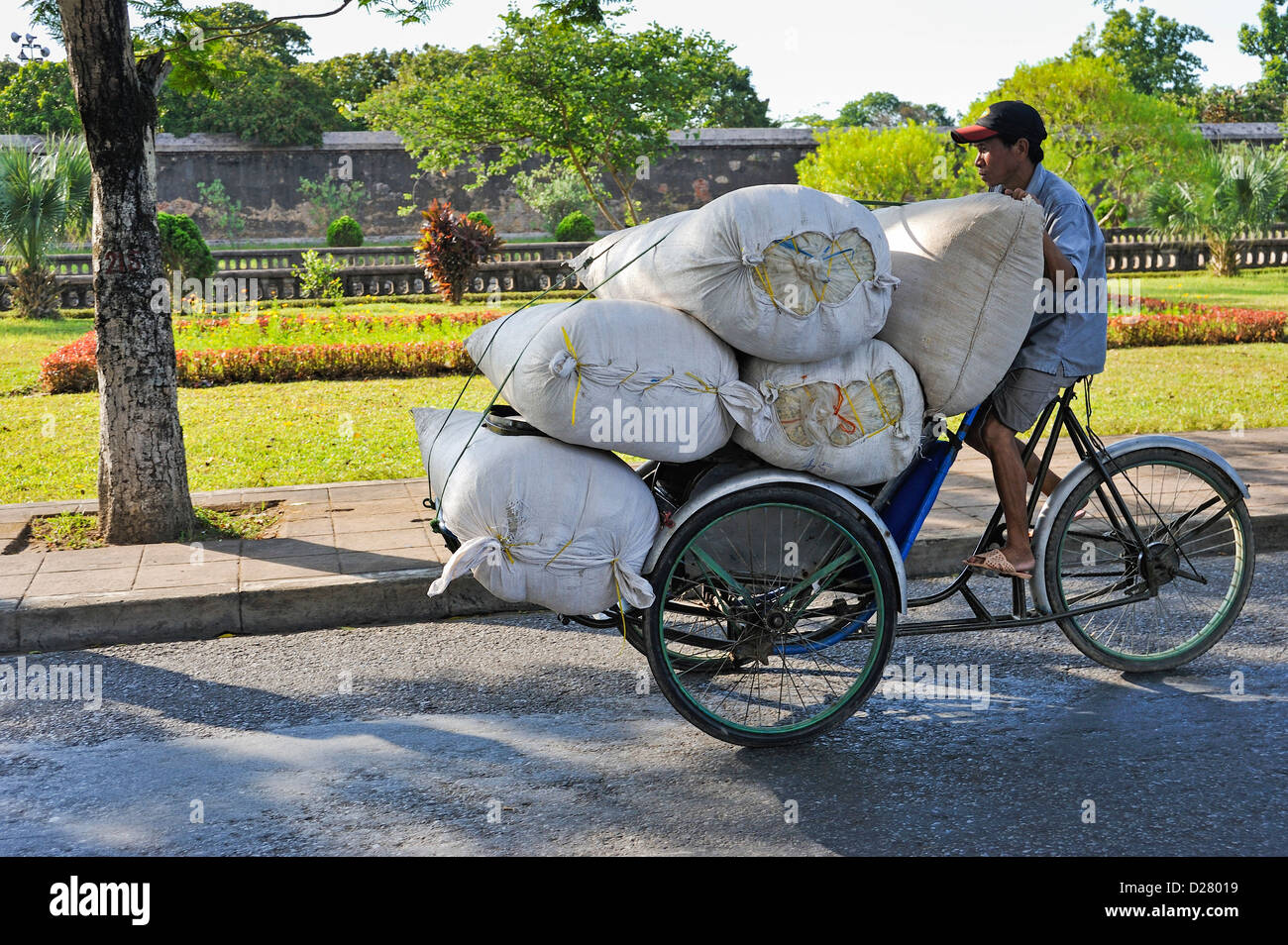 Hue, Vietnam - uomo che trasporta sacchi su un triciclo Foto Stock