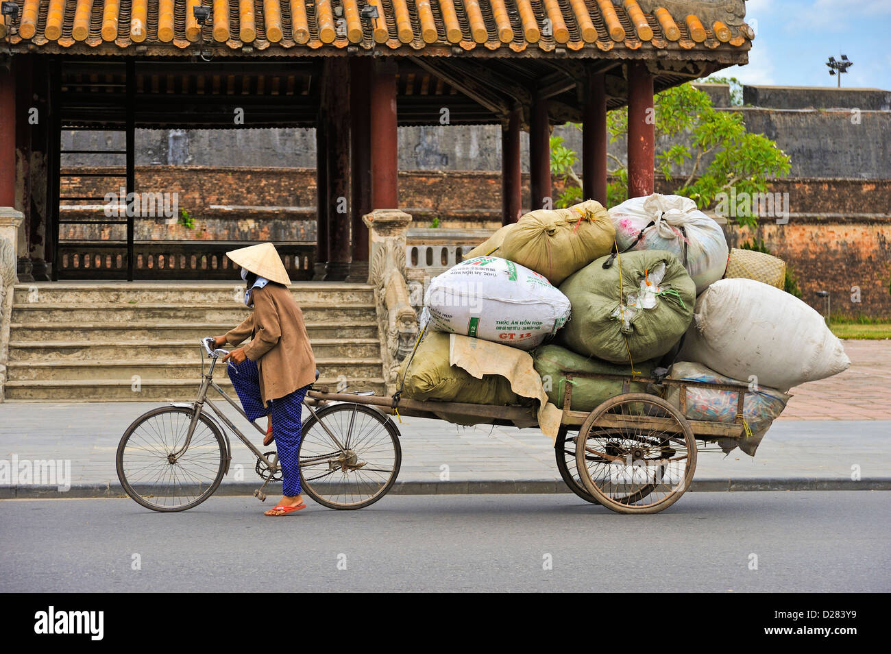 Hue, Vietnam - donna che tira un carico molto grande su un carrello per biciclette, gente che lavora Foto Stock
