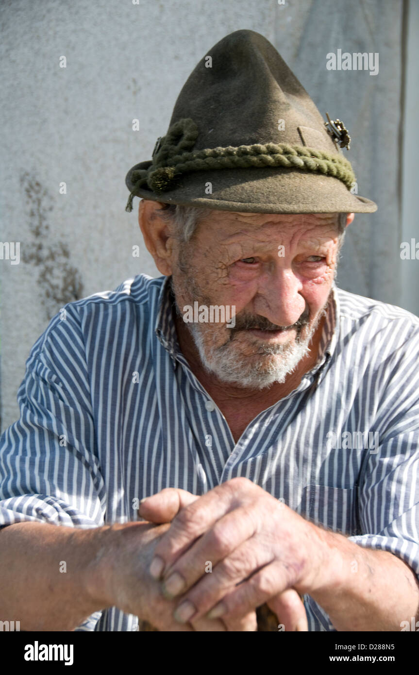 Un anziano italiano locale con il suo tradizionale cappello tirolese  risiede nel ben conservato villaggio rurale di montagna medievale di 'Tenno  Foto stock - Alamy