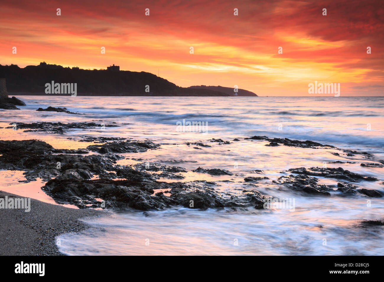 Sunrise catturato da Falmouth's Gyllyngvase Beach , con il Castello di Pendennis in distanza. Foto Stock