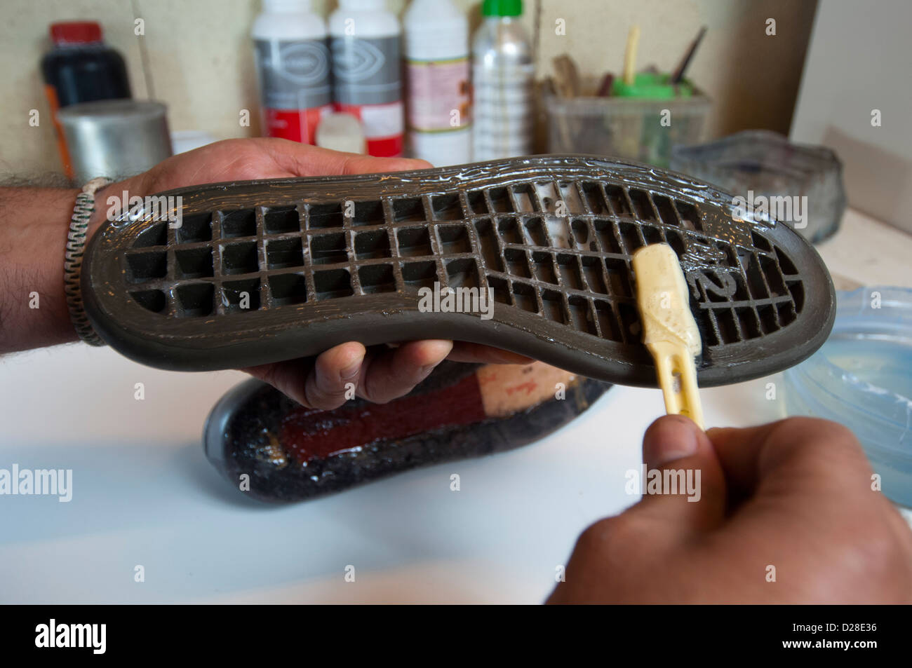 Una scarpa maker si applica il collante sulla suola in procinto di essere attaccato alla scarpa Foto Stock