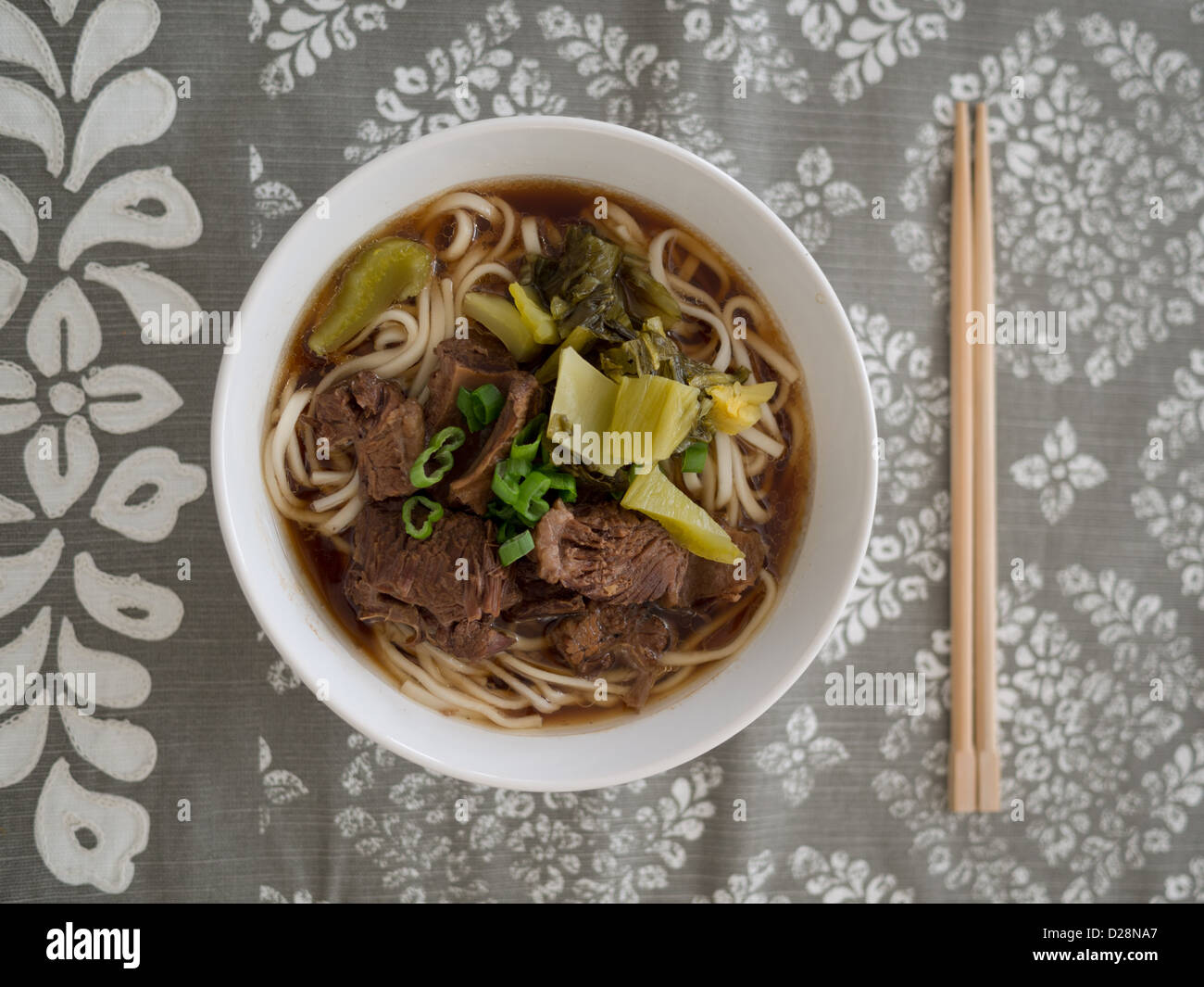 Home cotti Carni bovine Taiwanese noodle soup su una tabella grigia runner Foto Stock