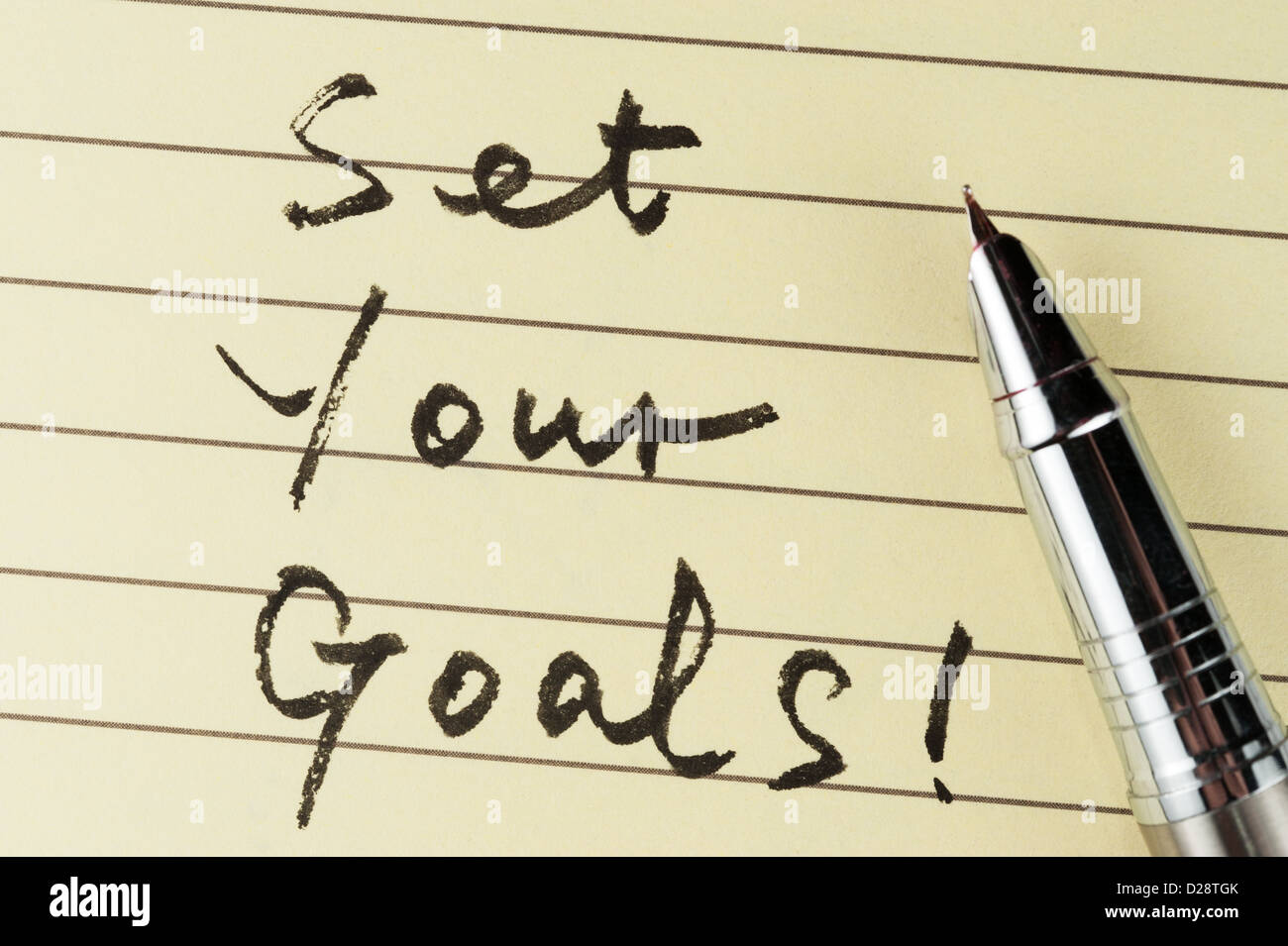 Imposta i tuoi obiettivi parole scritte su carta rivestita con una penna su di esso Foto Stock