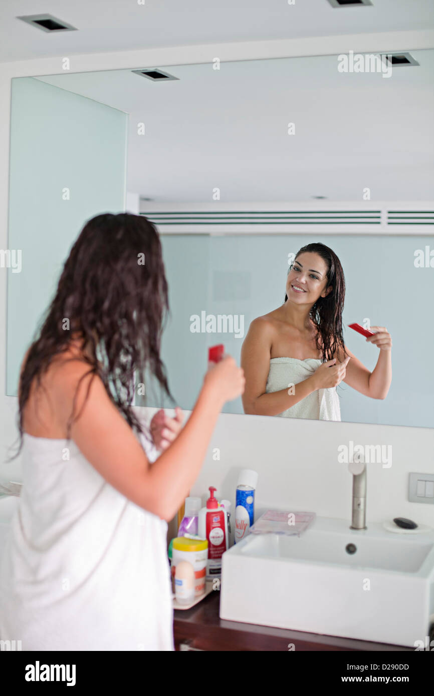 Brunette donna spazzolare i capelli davanti allo specchio Foto Stock